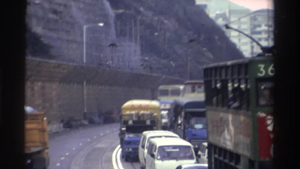 Hong Kong tram no. 36 in heavy traffic beside a rocky cliff face, filmed from inside a moving vehicle, circa 1982, 8mm film.