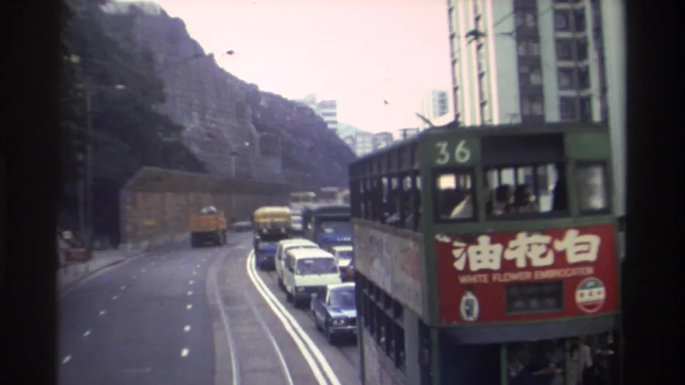 Hong Kong tram no. 36 displaying a legible White Flower Embrocation advertisement in Chinese and English, rocky hillside and buildings behind, circa 1982, 8mm film.