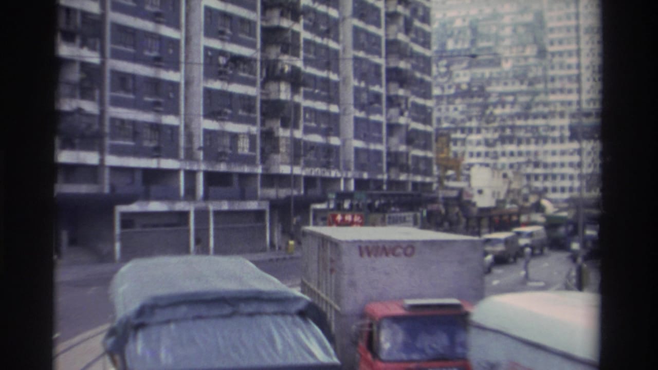 WINCO-branded container truck in Hong Kong traffic, with dense high-rise residential blocks and a red bus visible behind.