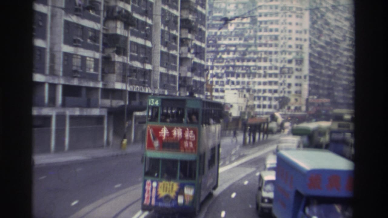 8mm footage of a green Hong Kong double-decker tram (route 134) bearing a red Lee Kum Kee Chinese-language advertisement, with dense tower blocks behind, circa 1982.