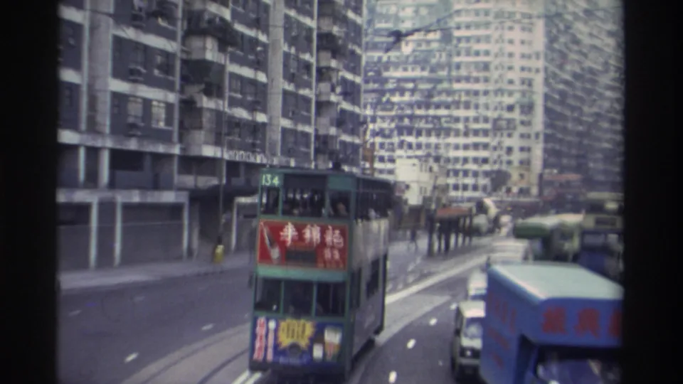 8mm footage of a green Hong Kong double-decker tram (route 134) bearing a red Lee Kum Kee Chinese-language advertisement, with dense tower blocks behind, circa 1982.