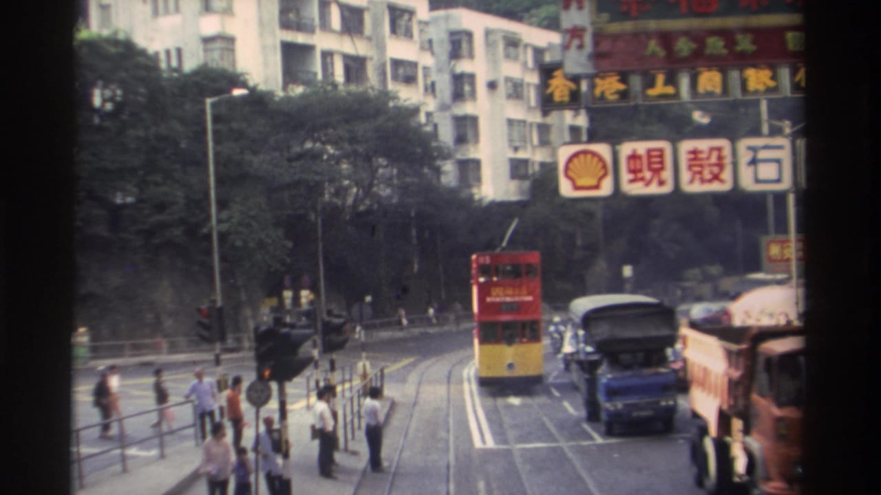 Hong Kong street, c.1982: double-decker tram on tracks, pedestrians crossing, Shell Chinese-language signage and commercial buildings visible.