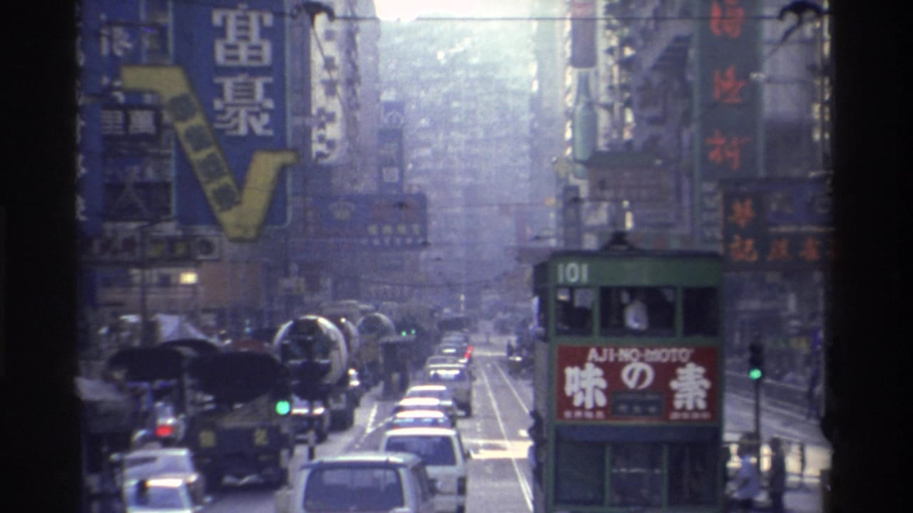 1982 Hong Kong street scene shot from vehicle interior; tram route 101 bearing Ajinomoto ad panel, flanked by Chinese neon signs on high-rises, Super 8 film grain visible.