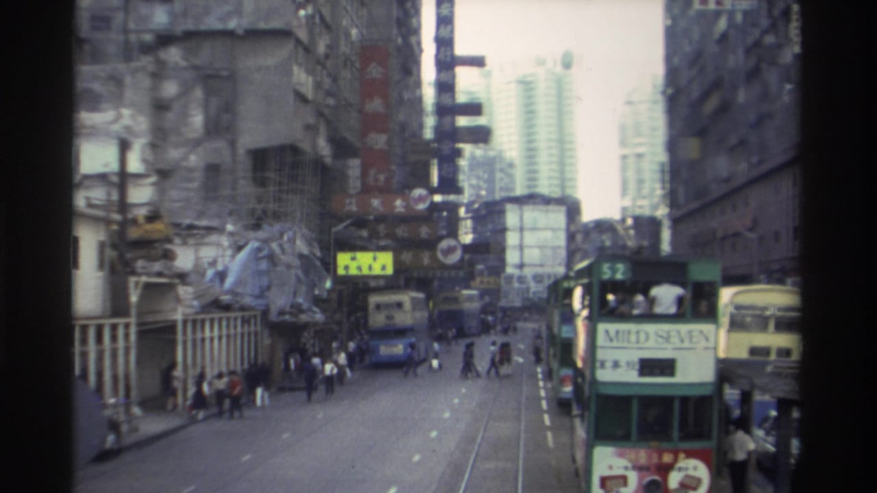 1982 Hong Kong street scene — trams on tracks including one advertising Mild Seven, dense Chinese commercial signage, mid-rise and high-rise buildings.