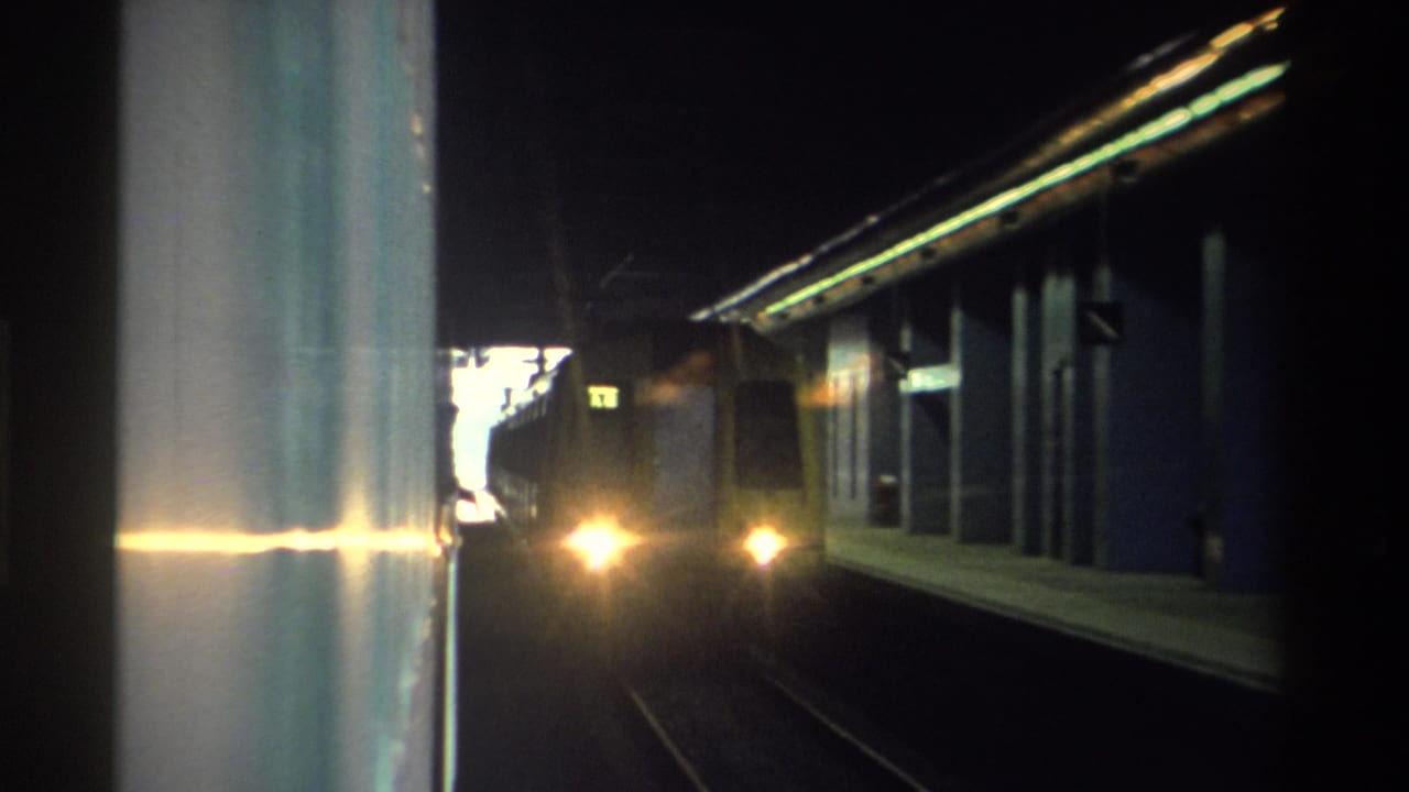 8mm home movie frame of a train approaching in a dark Hong Kong tunnel, c. 1982, with headlights causing strong lens flare and platform structure visible at left.