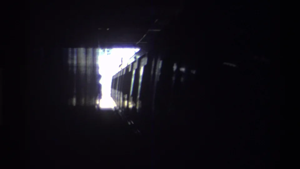 Handheld 8mm view from inside a Hong Kong railway tunnel, circa 1982, with the train advancing toward the bright tunnel mouth.