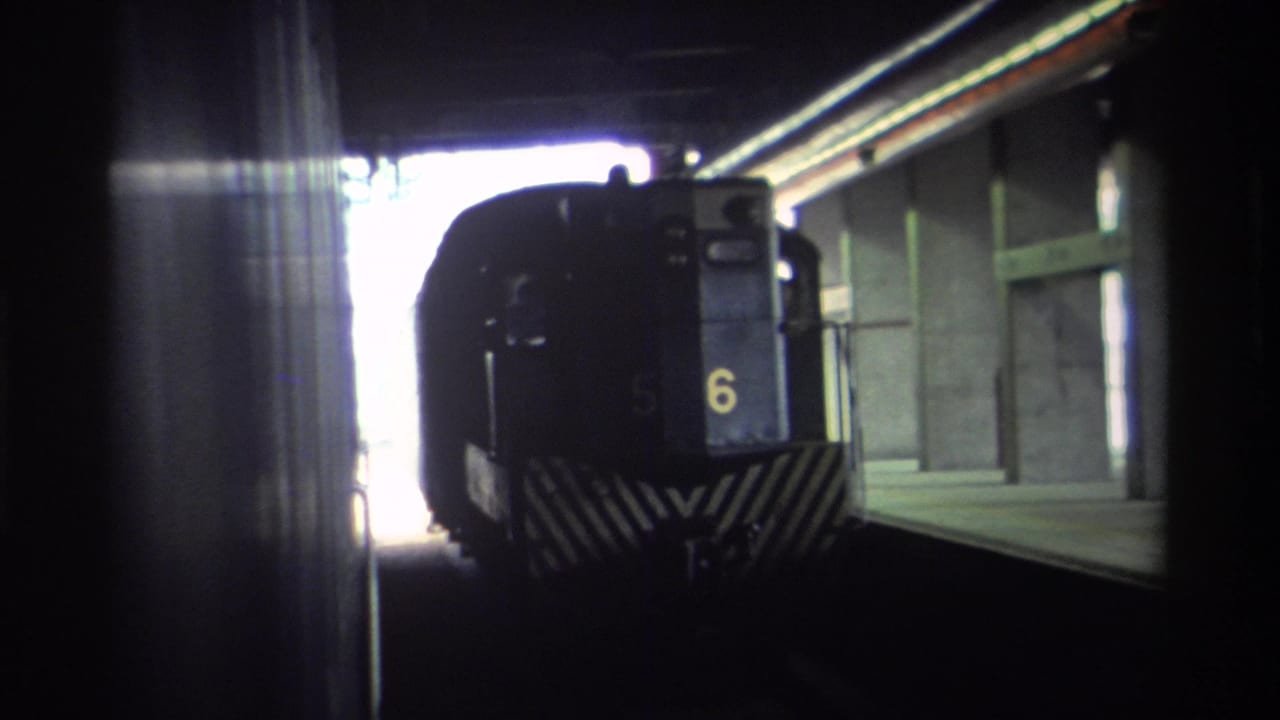 Hong Kong, 1982 — dark blue train numbered 6 with diagonal chevron markings seen from a covered station platform, captured on 8mm home movie film.