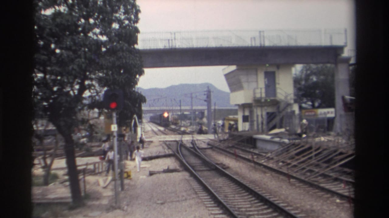 1982 Taiwan railway station; pedestrians move toward the boarding area as tracks converge beneath a concrete overpass and signal equipment.
