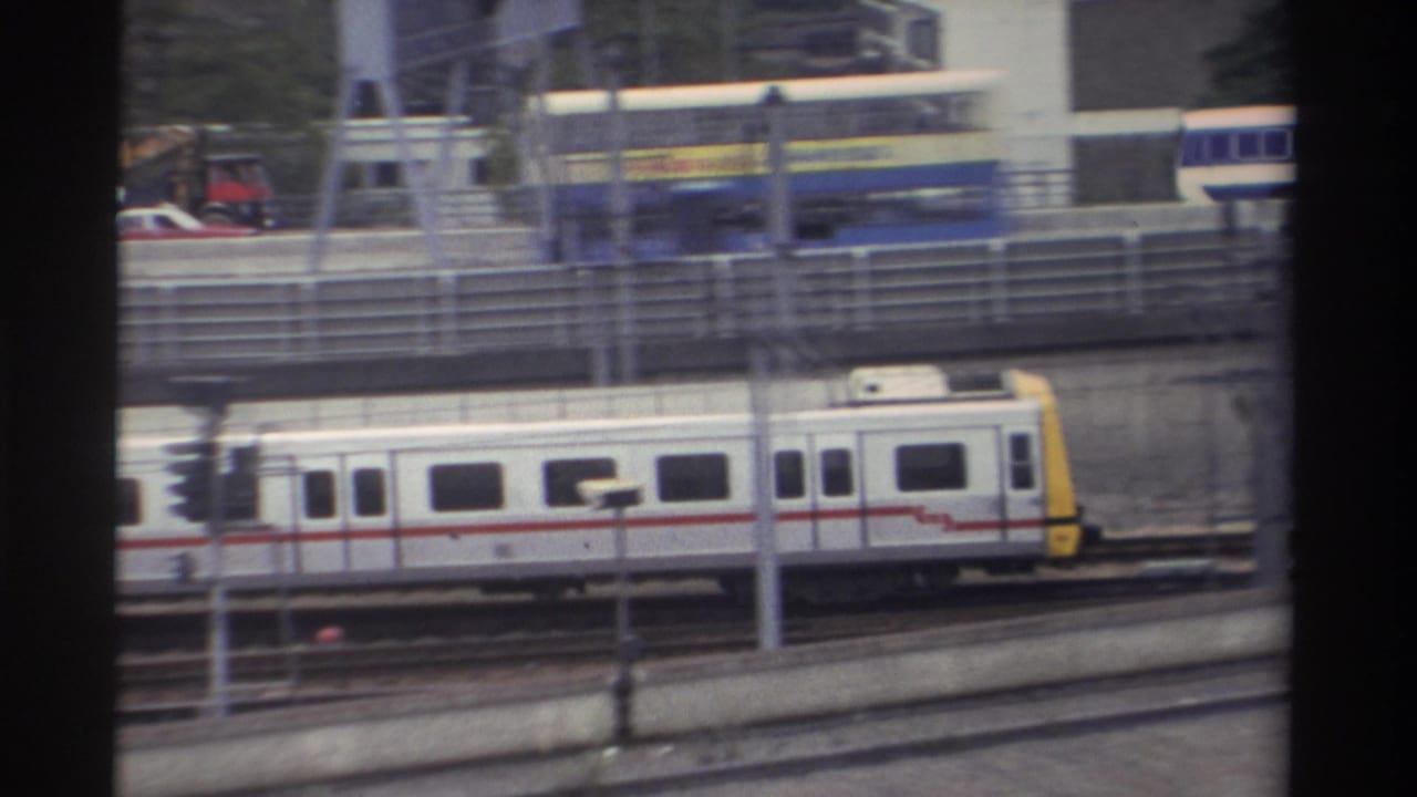 1982 Taiwan — yellow-fronted train car moving right along elevated tracks; billboard or sign partially visible at upper right; 8mm footage.