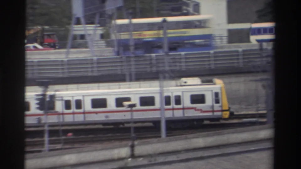 1982 Taiwan — yellow-fronted train car moving right along elevated tracks; billboard or sign partially visible at upper right; 8mm footage.