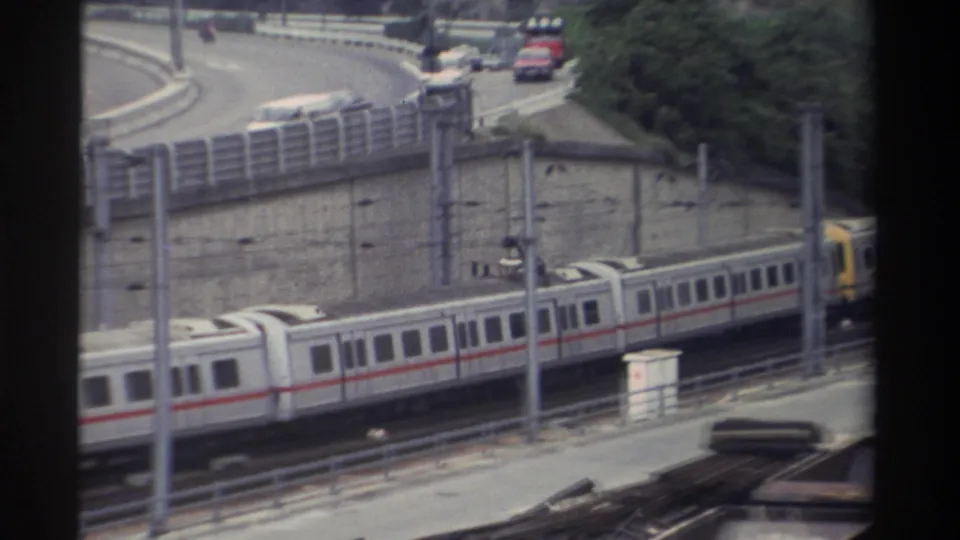8mm home movie from Taiwan, c.1982; trailing carriages of white and red train fill the lower portion, yellow cab car exiting right.
