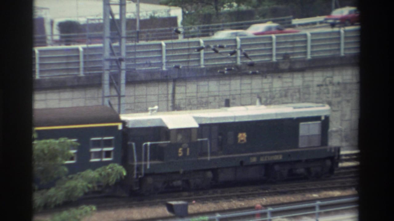 Dark green diesel locomotive numbered 51, white roof and yellow stripe, passes through an urban station area in Taiwan, circa 1982.