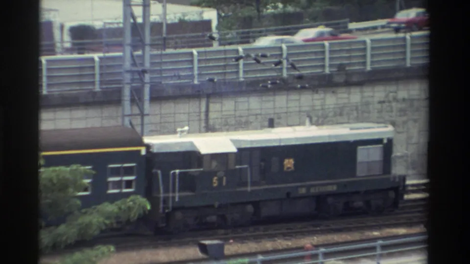 Dark green diesel locomotive numbered 51, white roof and yellow stripe, passes through an urban station area in Taiwan, circa 1982.