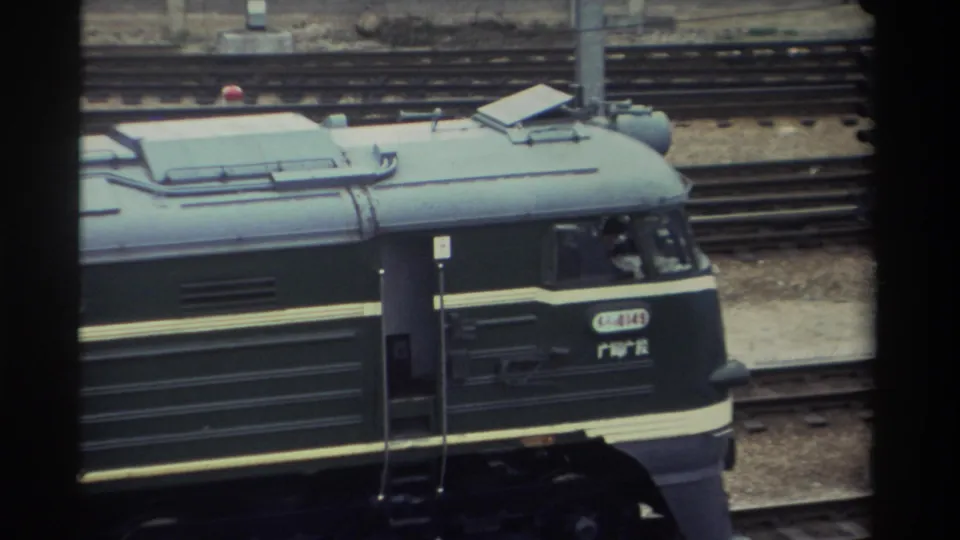 Close-up of a dark green locomotive with a yellow stripe and Chinese character markings consistent with 1980s Taiwan Railways Administration livery, on a rail yard track; red roof marker light visible.