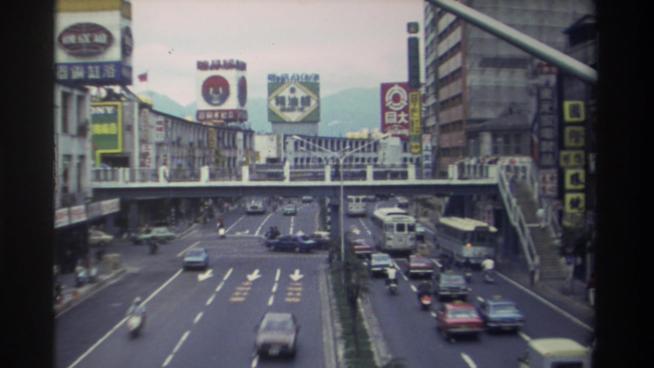 Elevated view of a multi-lane Taiwanese urban road with a pedestrian overpass and Chinese-character billboards, 1982.