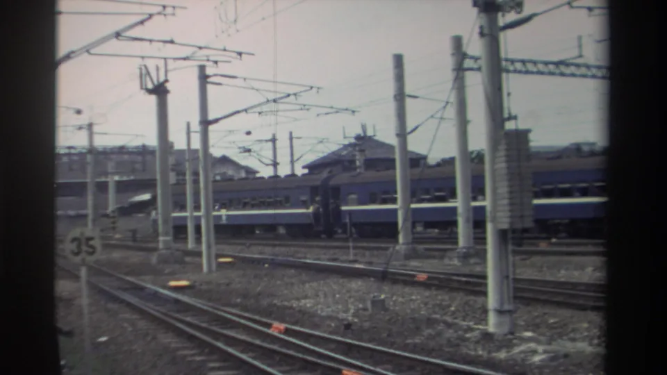 Elevated view of a Taiwanese rail yard, circa 1982, showing multiple parallel tracks, blue passenger rolling stock, overhead catenary wires, and a trackside '35' marker.