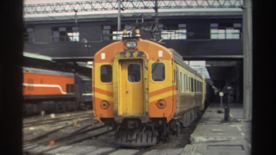 Orange and yellow train at close range in a Taiwanese station, 1982; distinctive livery and headlight unit clearly visible on 8mm film.