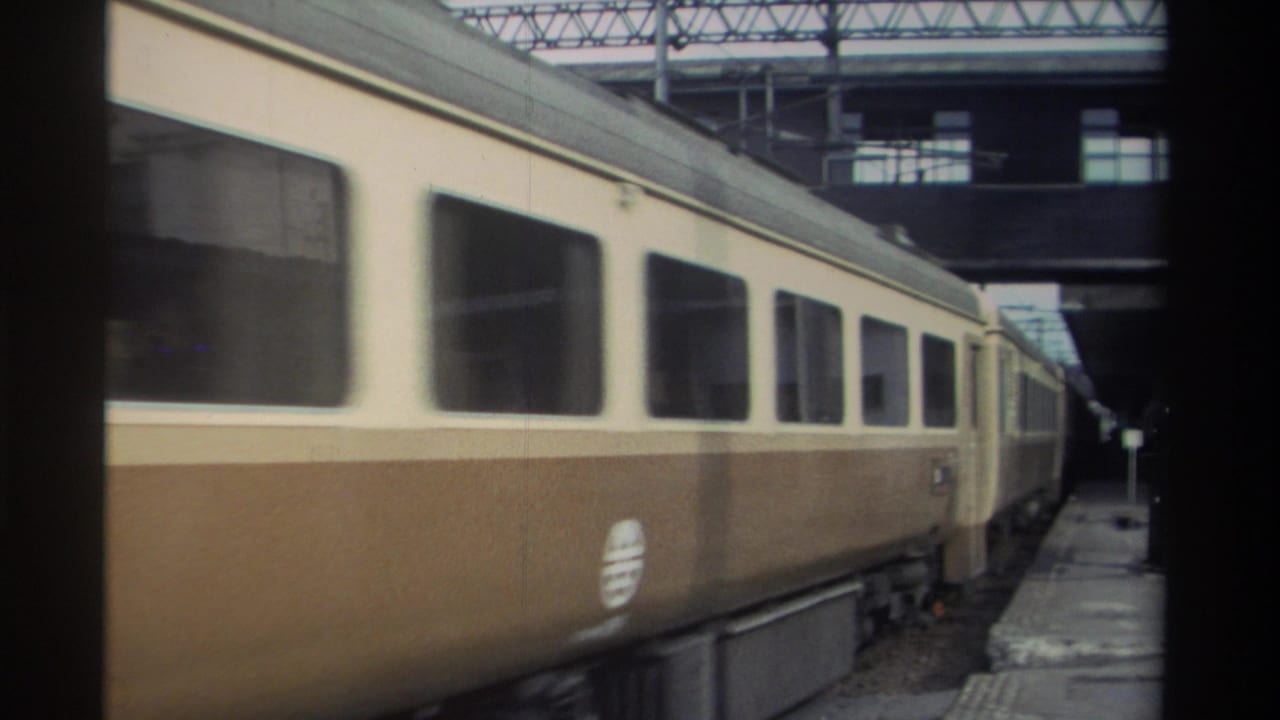 Two-tone cream-and-brown passenger train at a covered station platform, Taiwan, 1982, 8mm home movie footage.