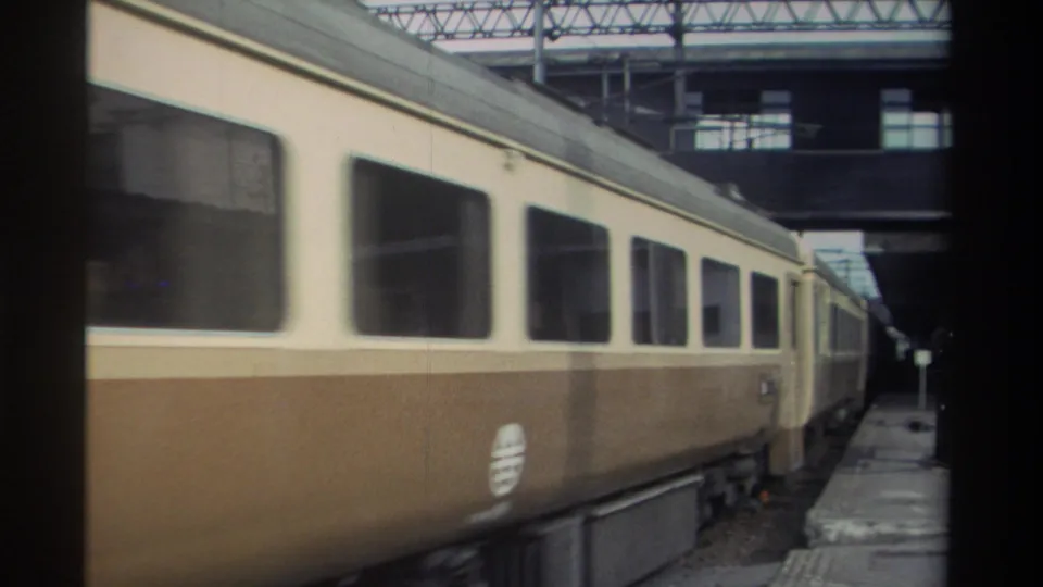 Two-tone cream-and-brown passenger train at a covered station platform, Taiwan, 1982, 8mm home movie footage.