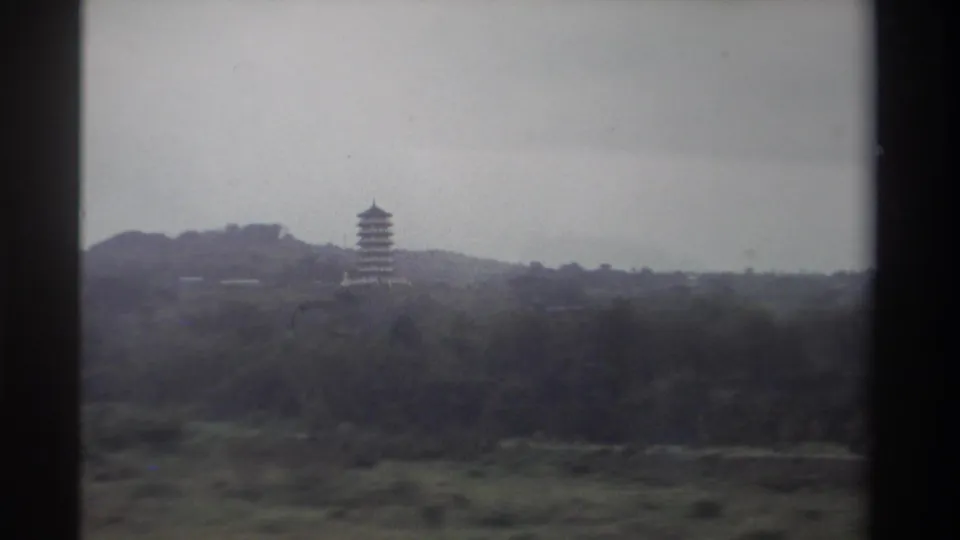 1982 Taiwan, 8mm film — pagoda on hilltop with visible rocky outcrop, dense green vegetation below, overcast sky.