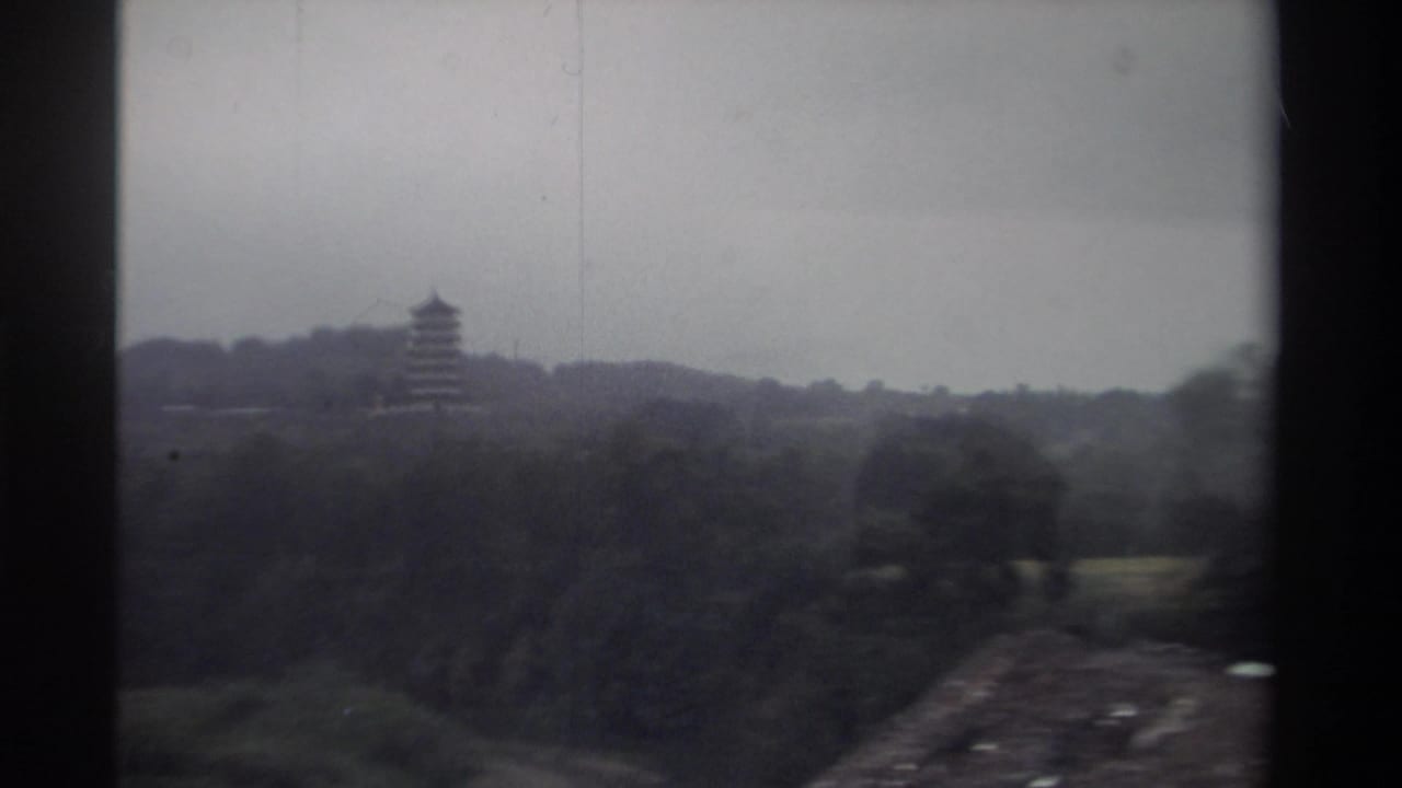 8mm travel footage of a pagoda on a hillside in Taiwan, circa 1982; a road or path emerges in the lower right as the filming vehicle passes.
