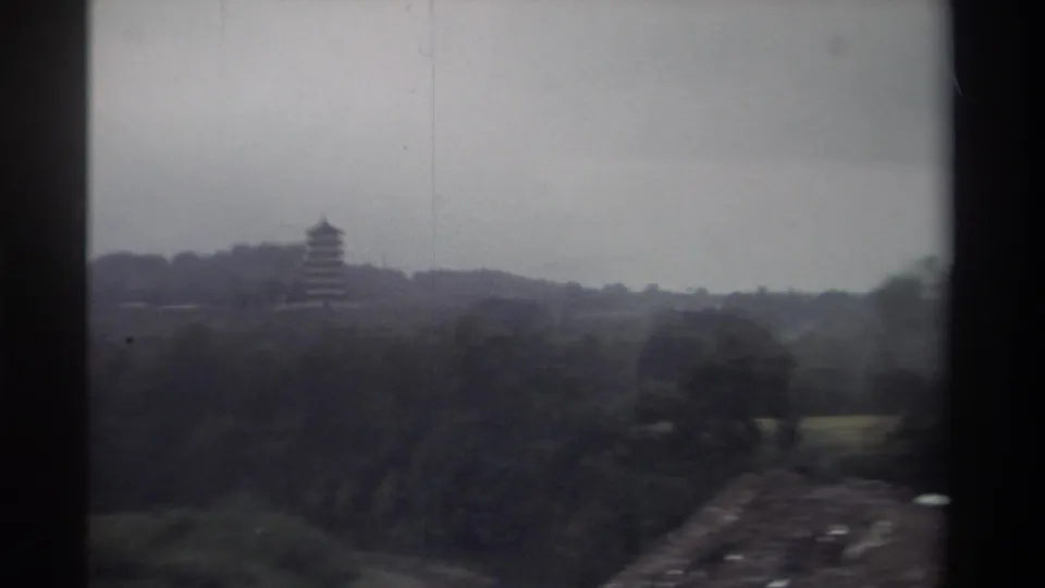 8mm travel footage of a pagoda on a hillside in Taiwan, circa 1982; a road or path emerges in the lower right as the filming vehicle passes.