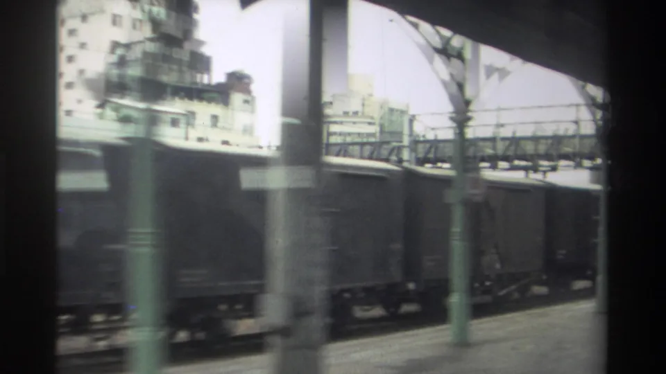8mm home movie from Taiwan, 1982 — lens flare and overexposure mark the final frame as freight wagons pass under a green railway canopy.