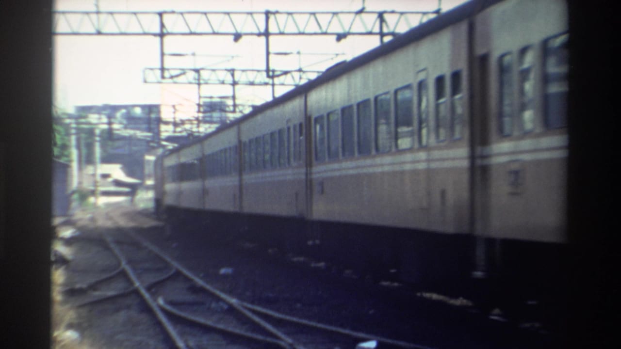 Passenger train passing beside multiple railroad tracks under overhead wires.