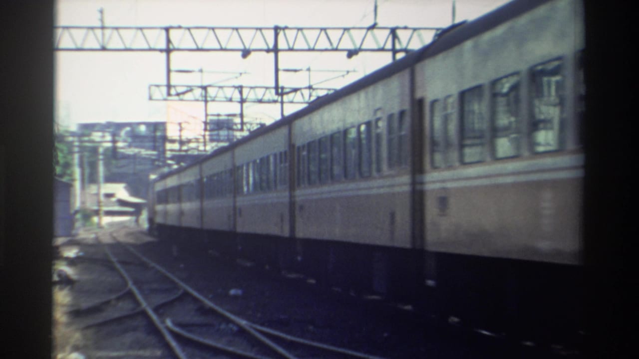 A fixed 8mm view in Taiwan shows the side of a passenger train passing through a multi-track rail area in 1982.