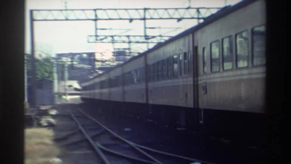 1982 Taiwan 8mm frame showing passenger carriages moving through multiple rails beneath overhead electrical gantries.