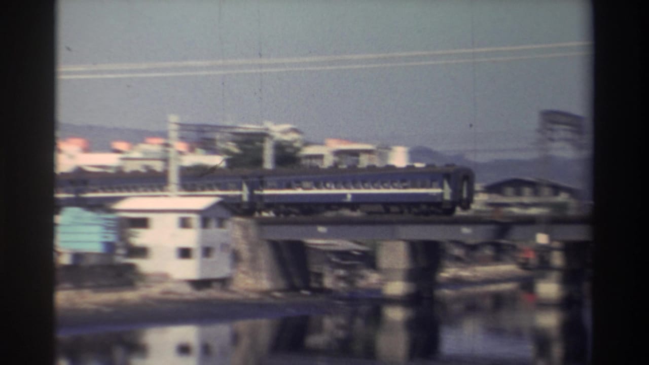 Blue passenger train crossing a concrete bridge over a river.