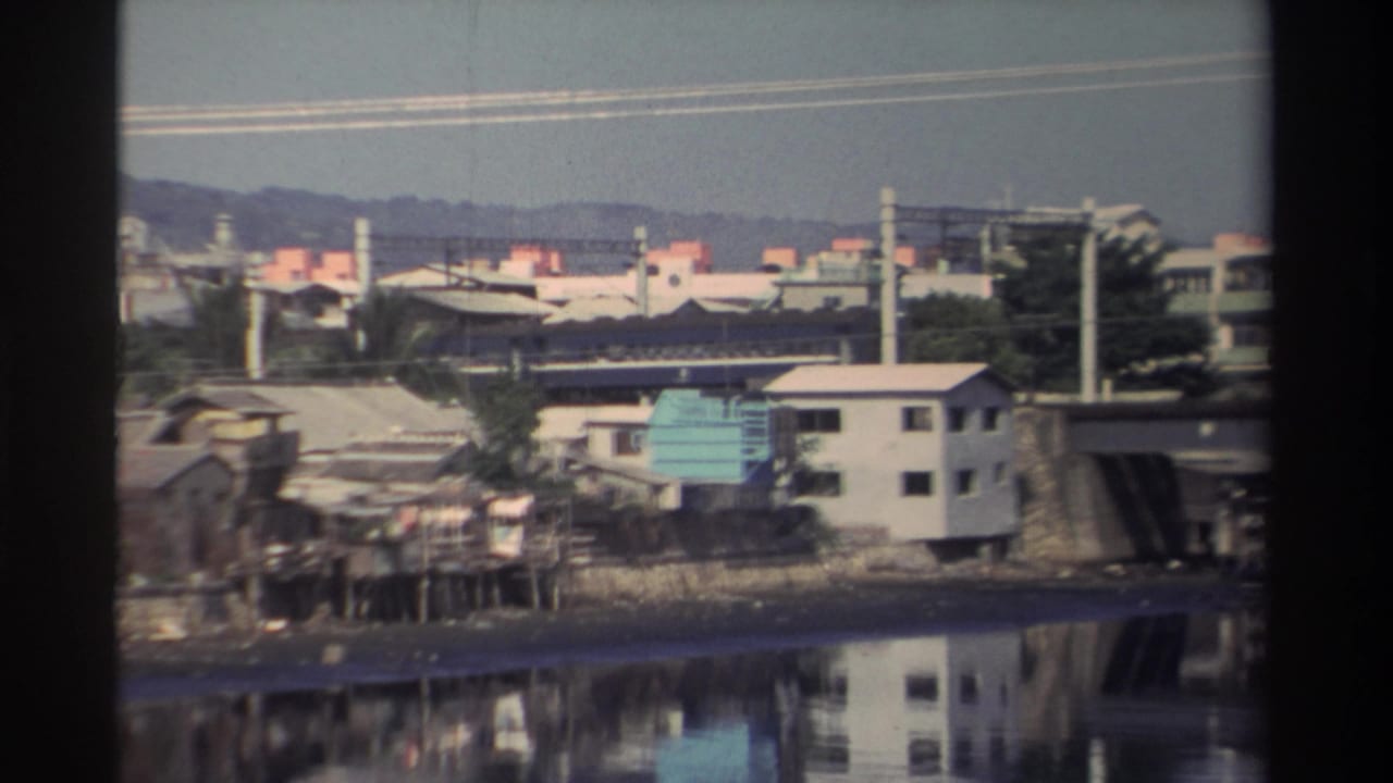 Waterfront buildings and bridge beside a calm river.