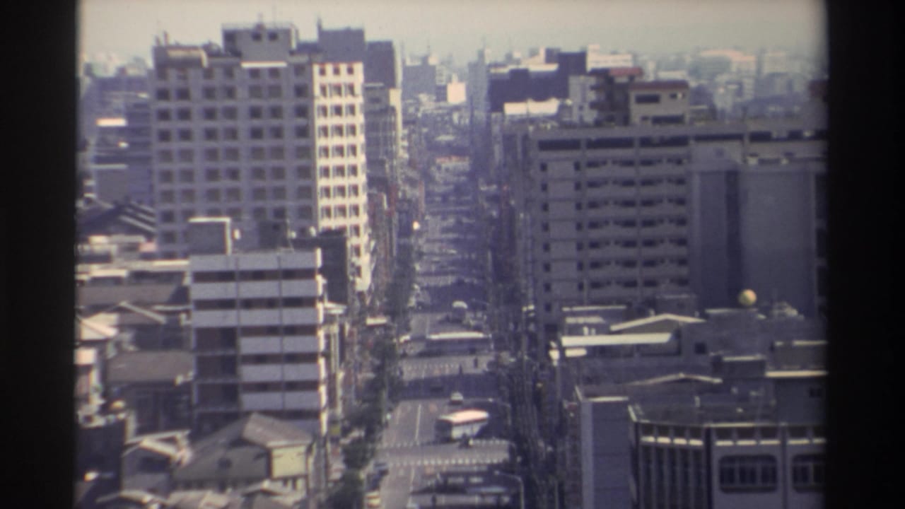 1982 Taiwan home-movie frame showing a hazy high-angle view down a city street lined with mid-rise buildings.