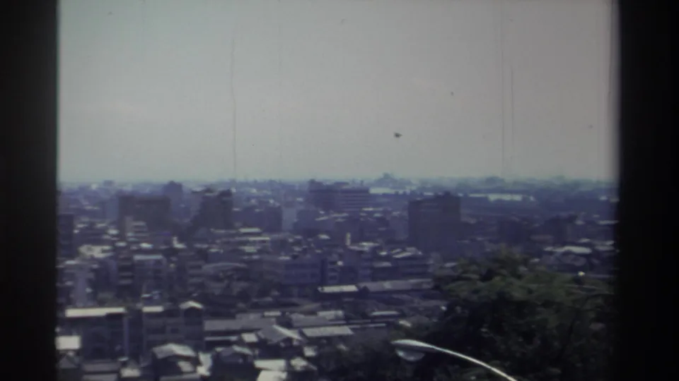 1982 Taiwan home-movie still showing a denser section of the city from above, with soft focus and faint vertical film scratches.