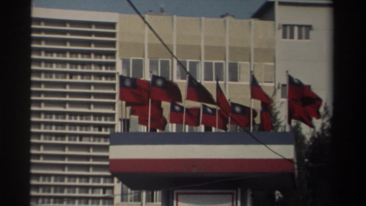 1982 Taiwan street view showing a modern building facade lined with multiple national flags and a striped awning in soft 8mm color.
