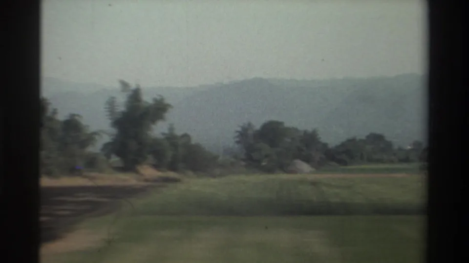 Rural Taiwan landscape in 1982 with green agricultural fields, tree clusters, distant hills, and vehicle-window framing.