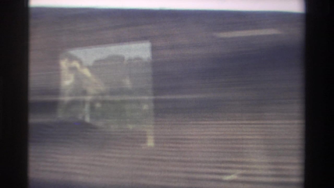 1982 Taiwan 8mm frame showing a blurred roadside view from a moving vehicle, with window reflection and horizontal motion streaking.