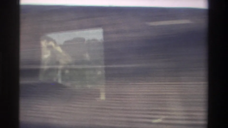 1982 Taiwan 8mm frame showing a blurred roadside view from a moving vehicle, with window reflection and horizontal motion streaking.
