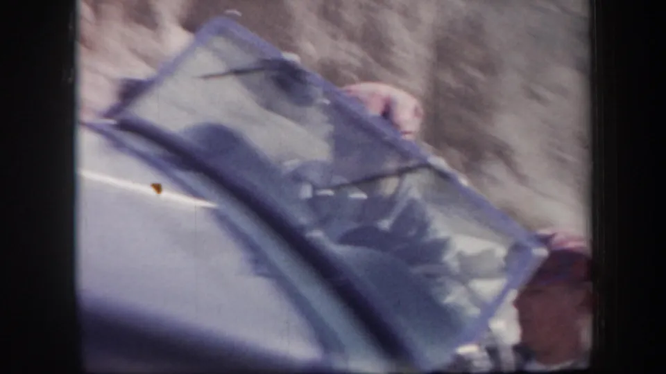 Close 1957 Arizona travel frame looking across a car window or windshield, with a person partly visible beside the vehicle.