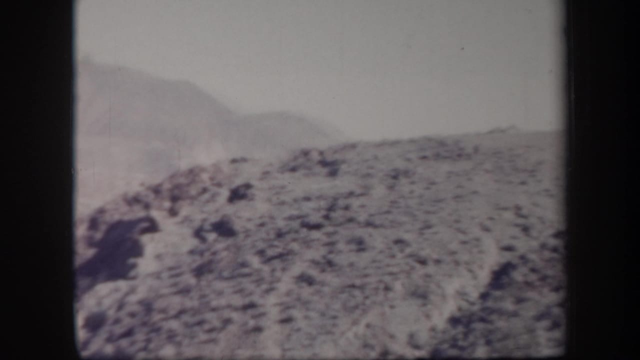 Vintage 8mm view of Arizona rocky terrain with distant rounded hills and faded mid-century film color.