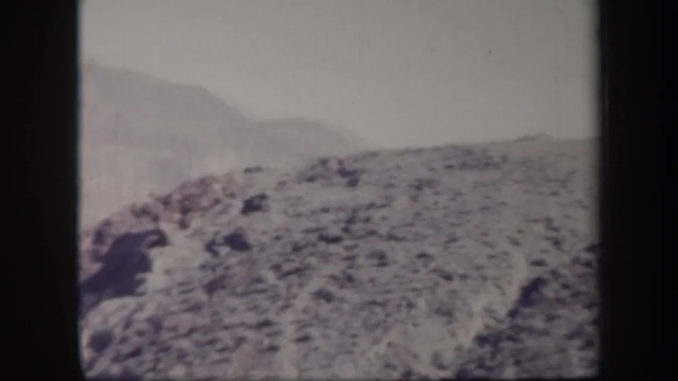 Vintage 8mm view of Arizona rocky terrain with distant rounded hills and faded mid-century film color.