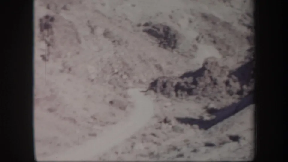 Faded 8mm frame of Arizona rocky terrain, with washed exposure and dark rock formations near the lower frame.