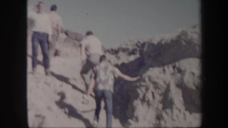 A small group of adult men appears on a sunlit rocky ridge in Arizona, filmed in soft, faded 8mm color.