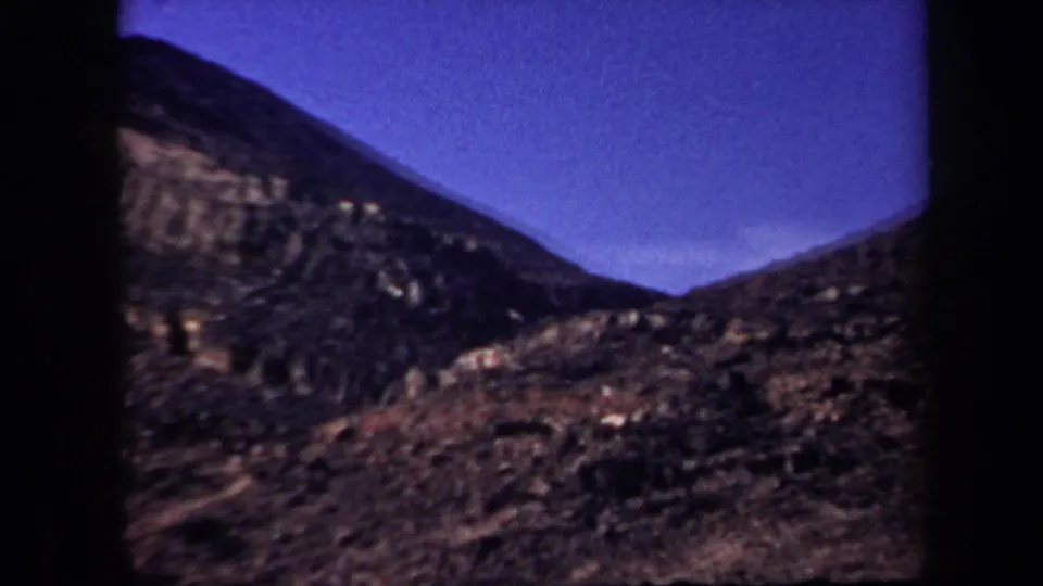 1957 Arizona 8mm view of a shadowed rocky valley area between hills, filmed in soft focus.