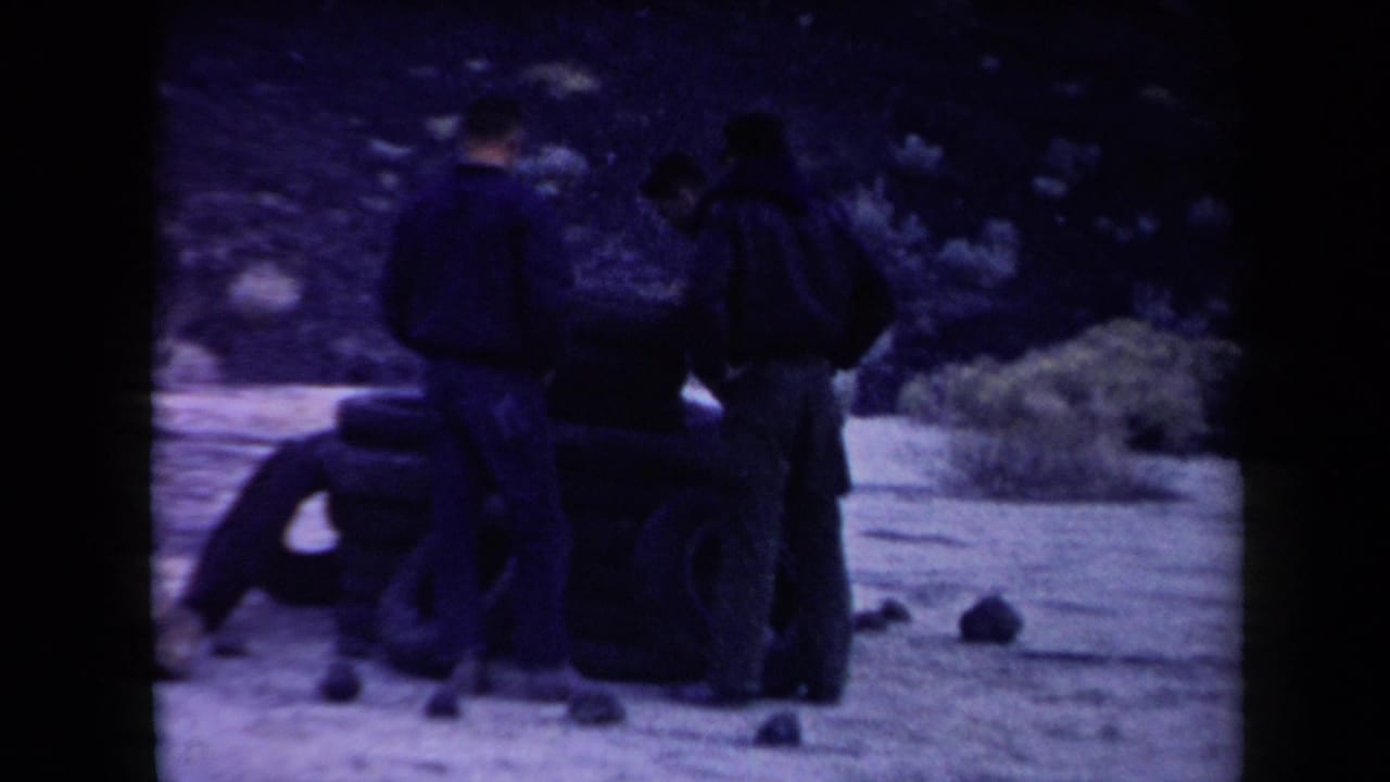 Three men work beside a growing stack of tires in a dry outdoor setting.
