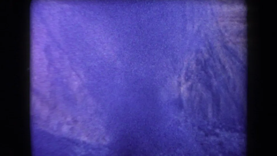 1958 Arizona 8mm frame with indistinct desert or mountain terrain, heavy grain, and purple-blue fading at the end of the clip.