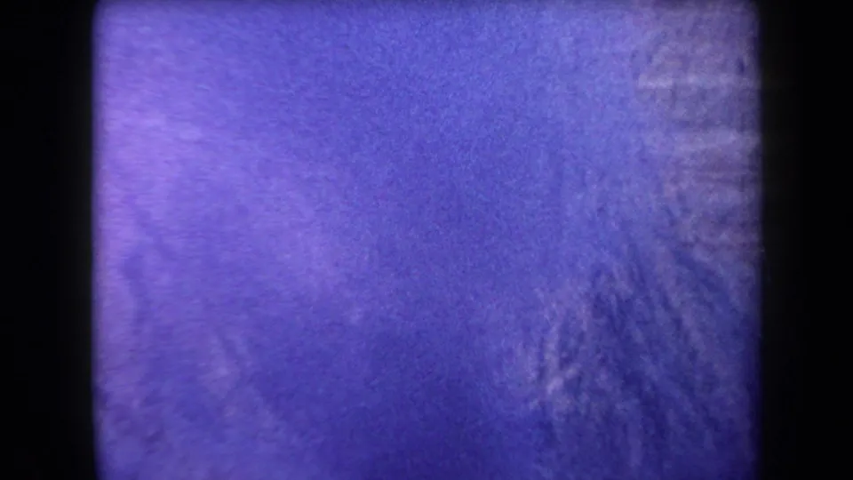 1958 Arizona 8mm frame showing a distant ridge with faint smoke and strong purple color shift from aged film stock.