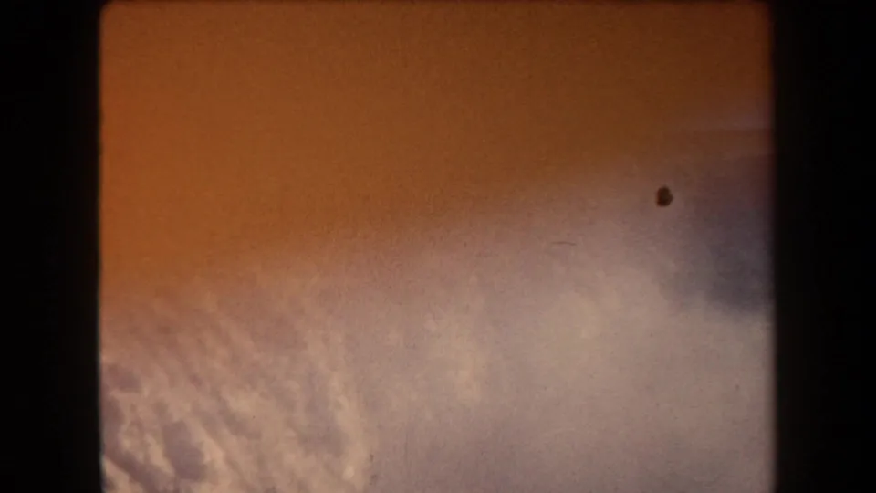 1958 Arizona 8mm frame showing an orange sky with pale cloud texture, soft exposure, grain, and dark gate edges.