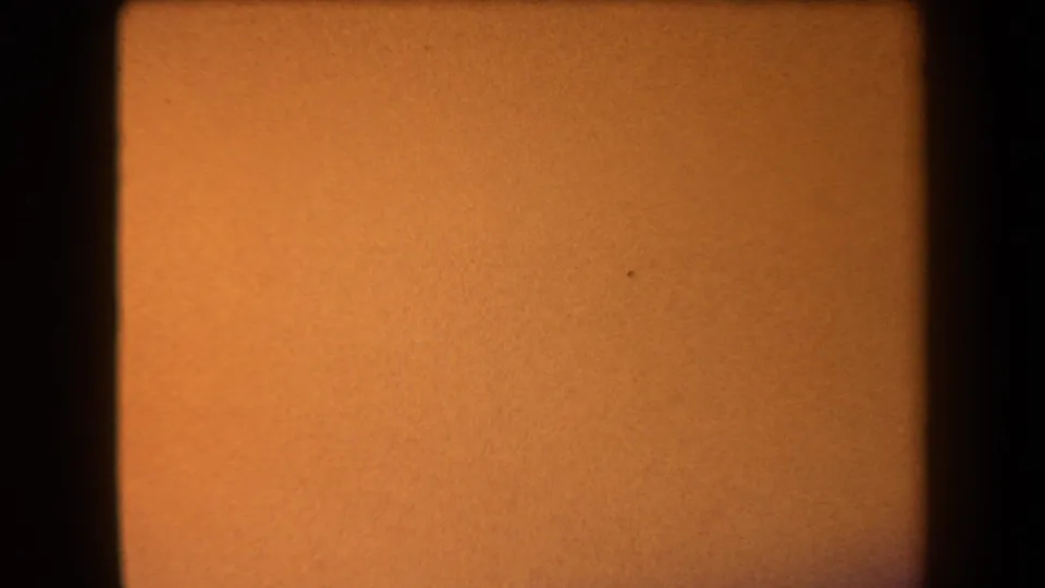 1958 Arizona 8mm frame with warm orange sky, tiny film specks, grain, and a dark border along the right side.