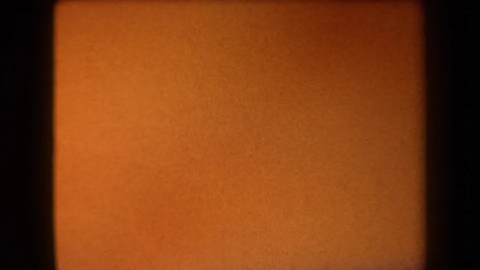 1958 Arizona 8mm frame with a warm orange surface, a dark vertical frame edge, soft blur, and aged film texture.